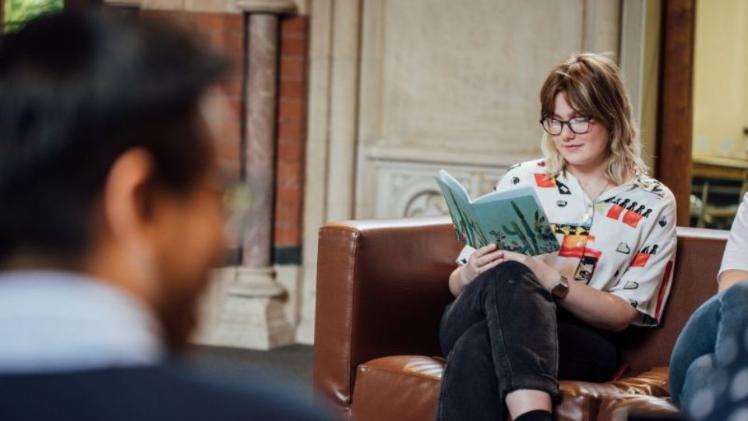 student sitting on a chair reading